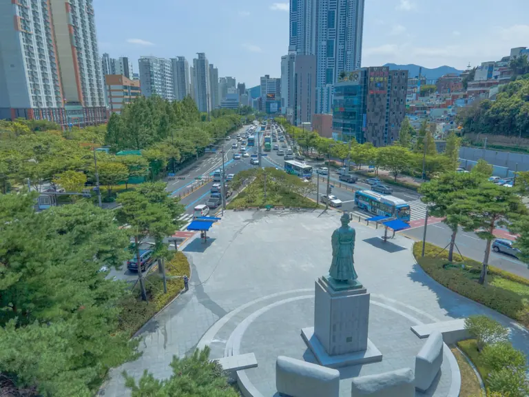 Bustling aerial view of downtown Busan showcasing cityscape and statue.