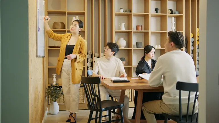 A group of professionals brainstorming and planning on a whiteboard in a stylish office setting.
