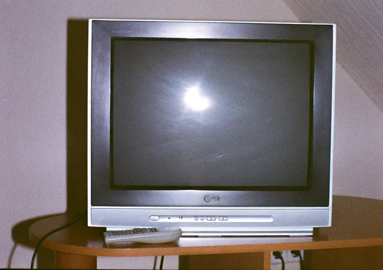 A television set with a remote control on a table