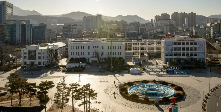 white and blue round fountain in the middle of city buildings during daytime