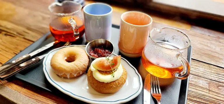 Delightful breakfast setup with tea, pastries, and cups on a wooden table.