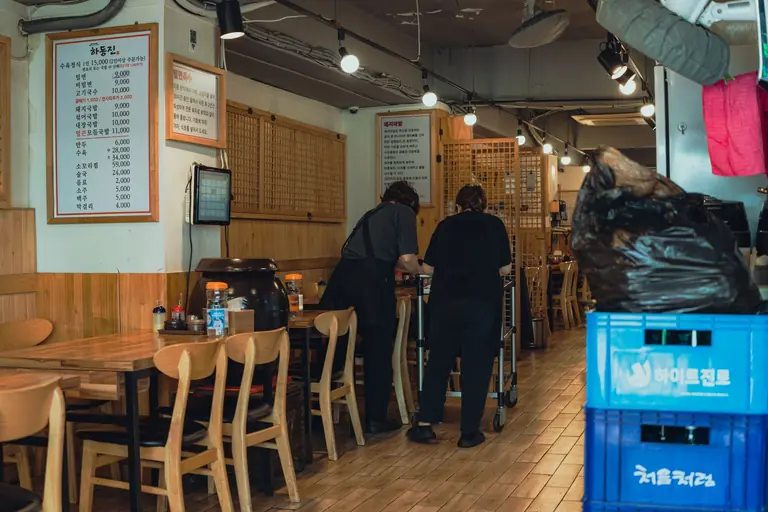 Warm interior of a traditional Korean restaurant with staff organizing tables in Seoul, South Korea.
