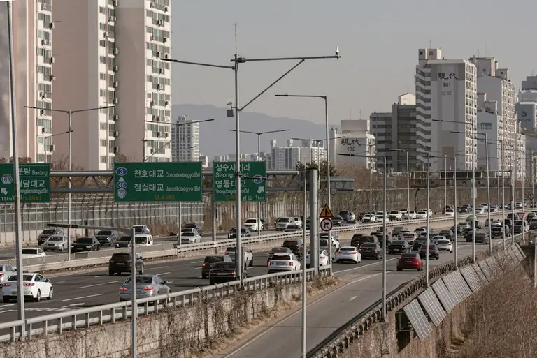 A busy highway with lots of traffic and tall buildings