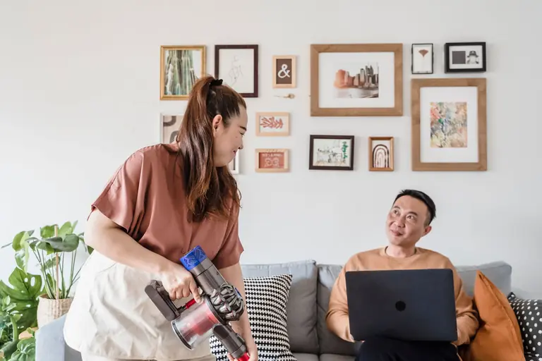 Couple enjoys cleaning the living room together with smiles and mutual support.