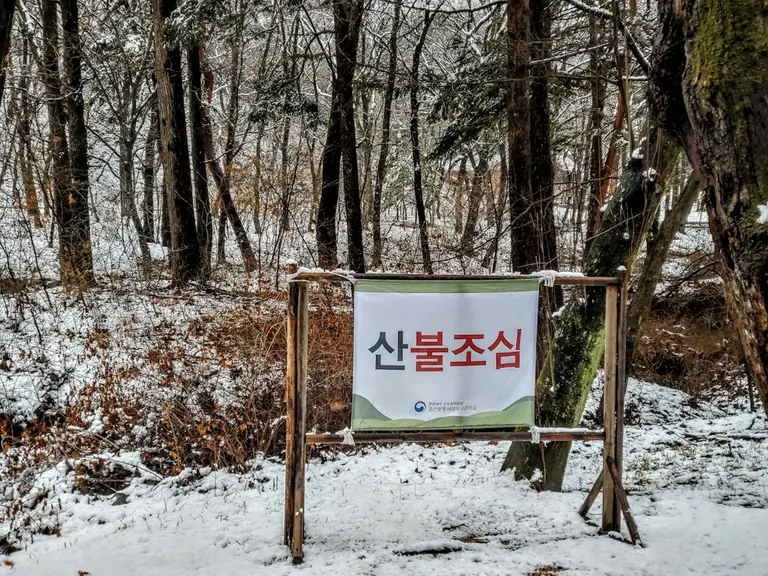 a sign that is in the snow by some trees