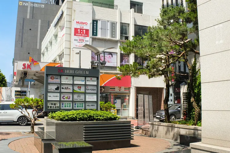 Bright and bustling urban scene in Seoul, showcasing modern architecture and greenery.