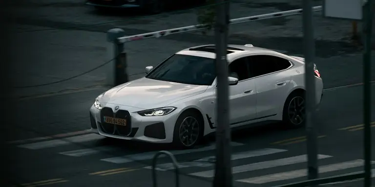 a white car driving down a street next to a parking meter